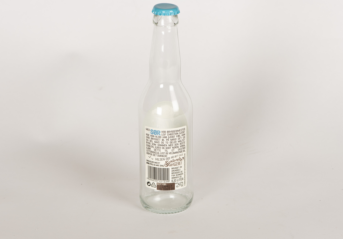 Glassflaske for øl. Blankt glass. Metallkork sitter på flasken, innholdet er tømt ut.