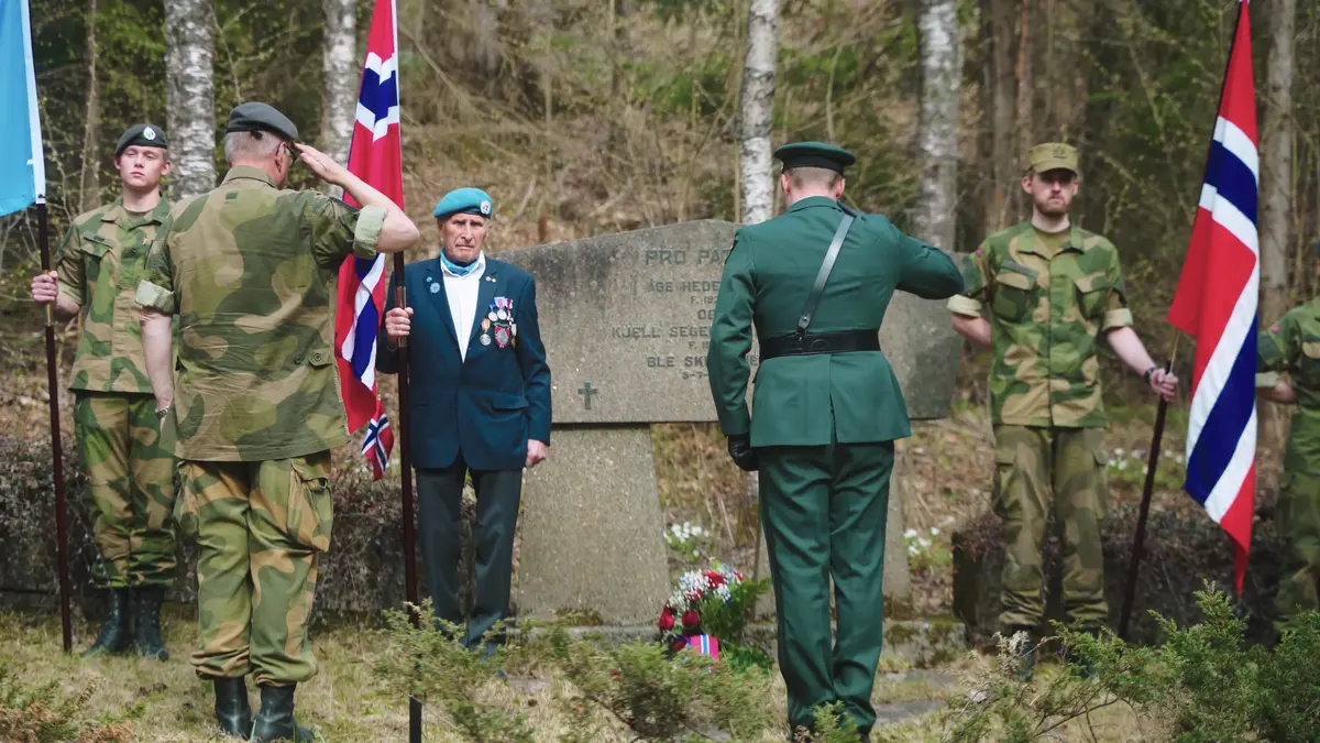 Fotografi tatt 8. mai 2023 ved nedre rettersted. To norske flagg på hver side av steinen, minnesmerke, fem menn i fotografiet.