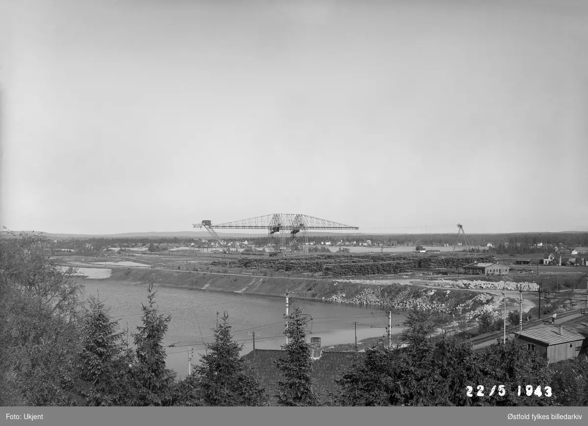 Kran for opptak av sagtømmer og tømmerlager til Borregaard fabrikker, Opsund i Sarpsborg 1943. Bildet viser at det var sparsomme tømmerlager under 2. verdenskrig.