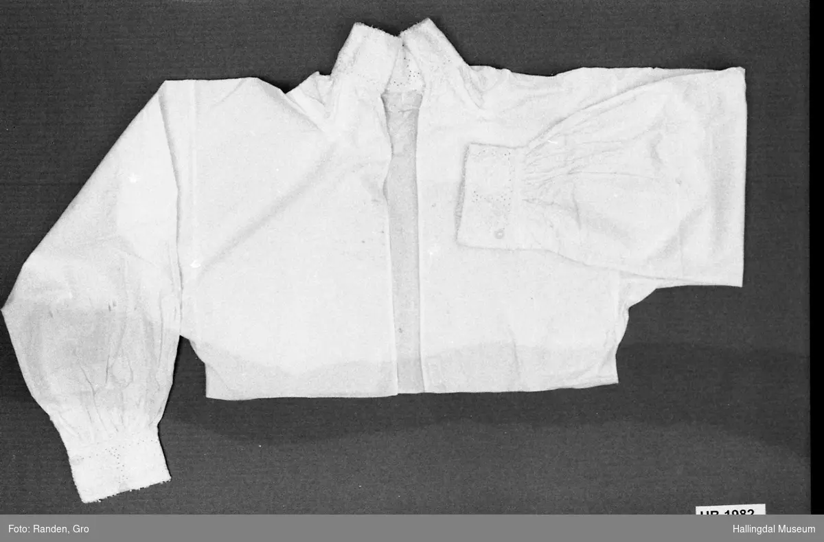 Skjorte, kvinneskjorte, ovadeld i hvitt bomullslerret. Kvirsøm på hals- og ermkrager.