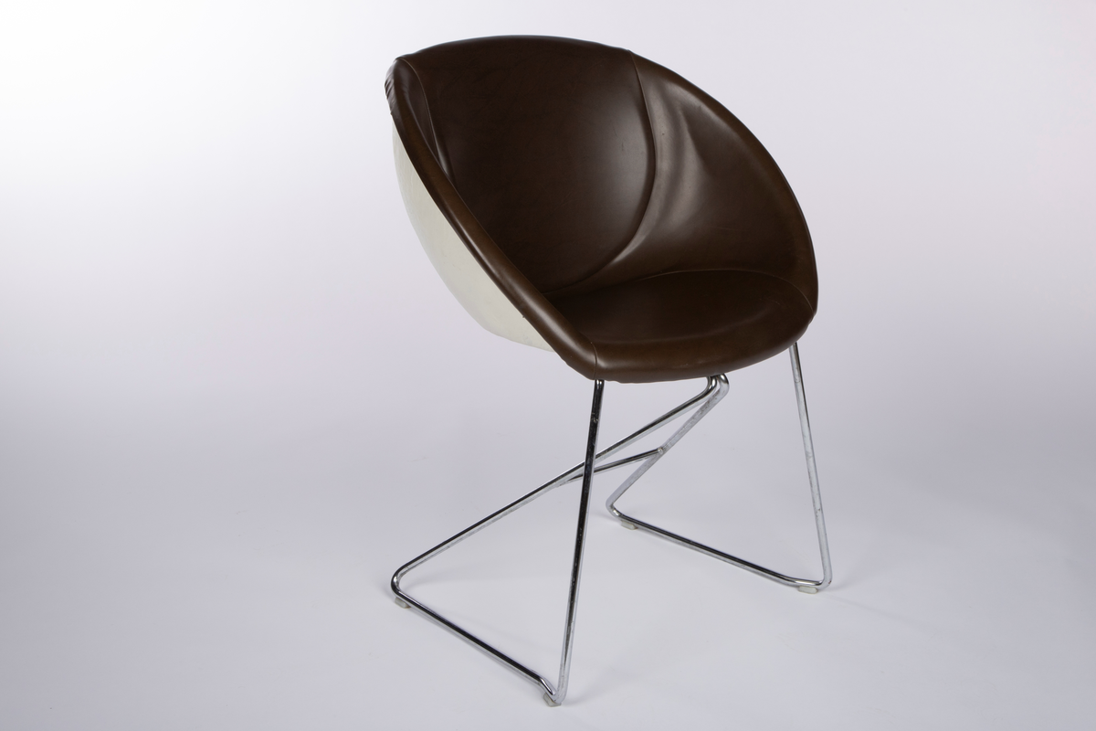 Tilnærmet halvkuleformet stol med hvit skall av plast (glassfiberarmert polyester) på et lett forkrommet stålrørunderstell. Mørkebrunt avtagbart trekk av skai (skinnimitasjon). Stabelbar.