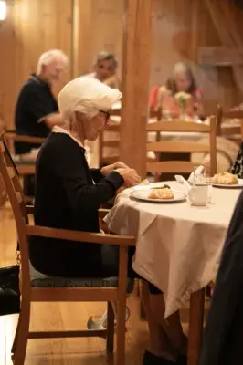 En dame sitter ved et bord og spiser. 