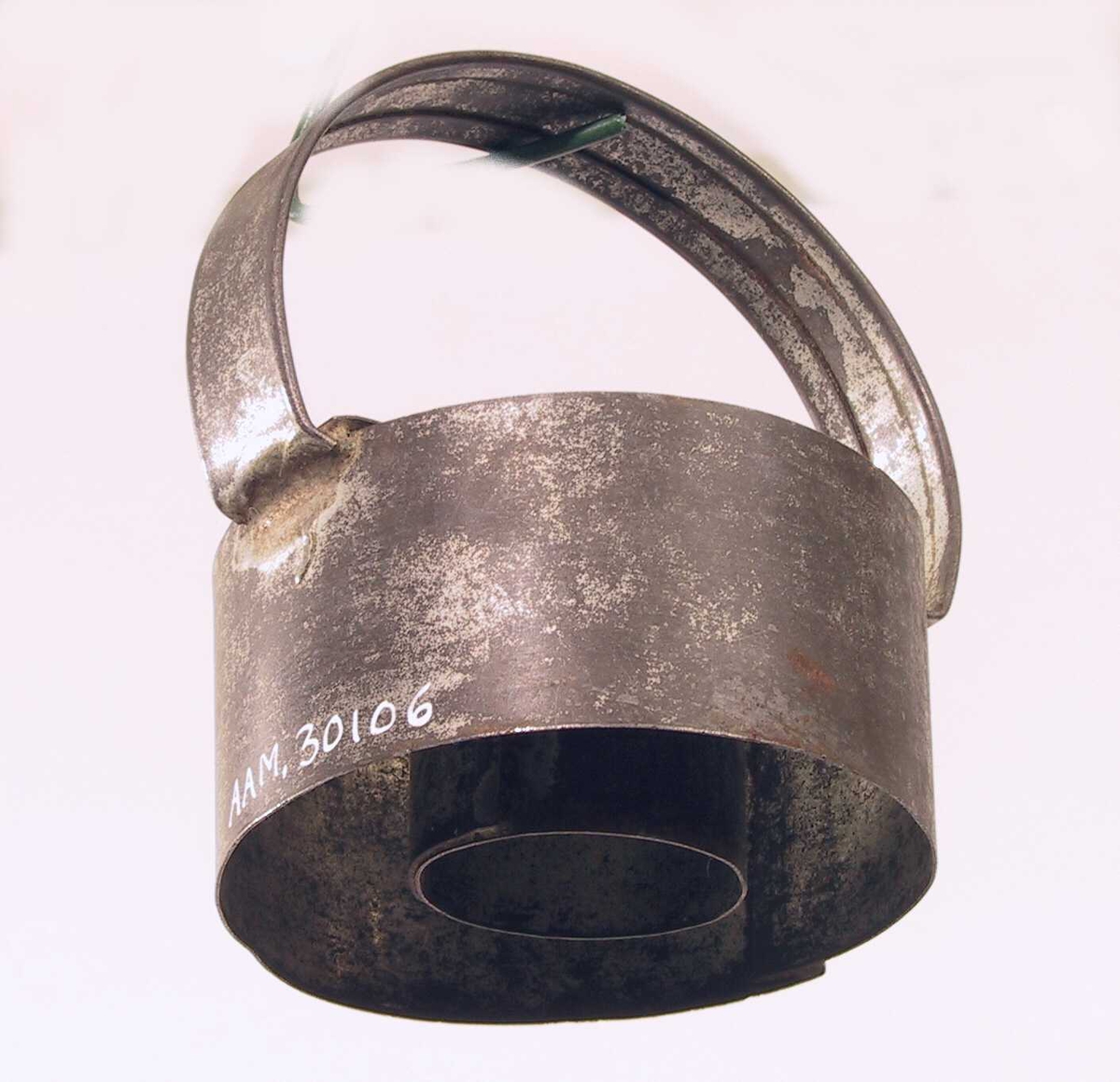 Liten sylinder av tynn jernplate med en større utenfor, festet sammen med et bånd av jern på tvers over begge og et håndtak festet ved hver ende av båndet. 
