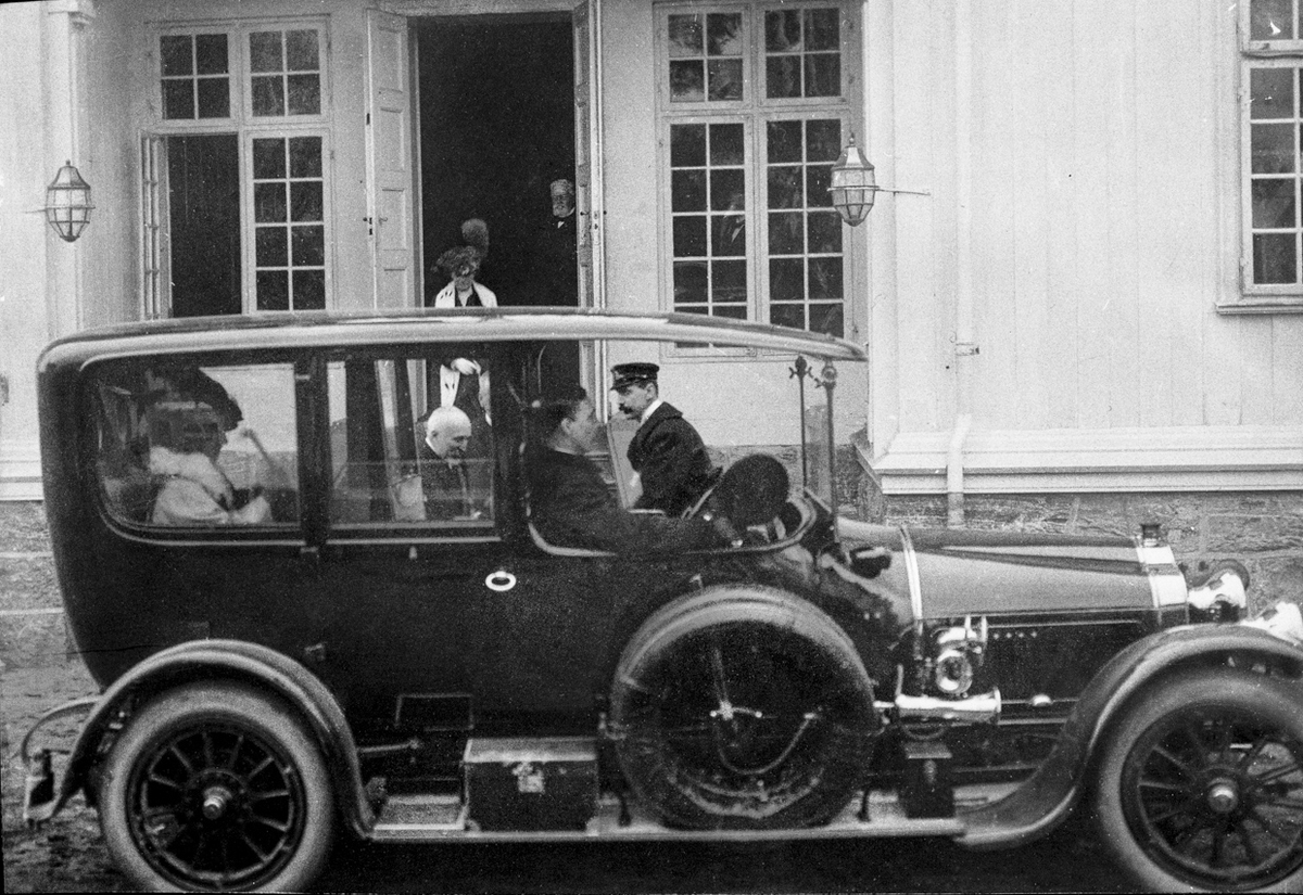 16. mai. Dronning Maud i bilen. Kong Haakon i bakgrunnen. Dronningen reiste tilbake til Oslo sammen med prins Olav på ettermiddagen.

Bilen er av merket "Minerva" med reg. nr. A-2, årsmodell 1913. Kongen holdt seg til det belgiske merket Minerva på 10-tallet – og gikk visstnok ikke til innkjøp av bil før den første motorvognloven var trådt i kraft 1. april 1913. Bilen er bevart og står på Norsk Teknisk Museum. 
Kilde: Ivar E Stav/T Krogsæter. (4.2.2014)