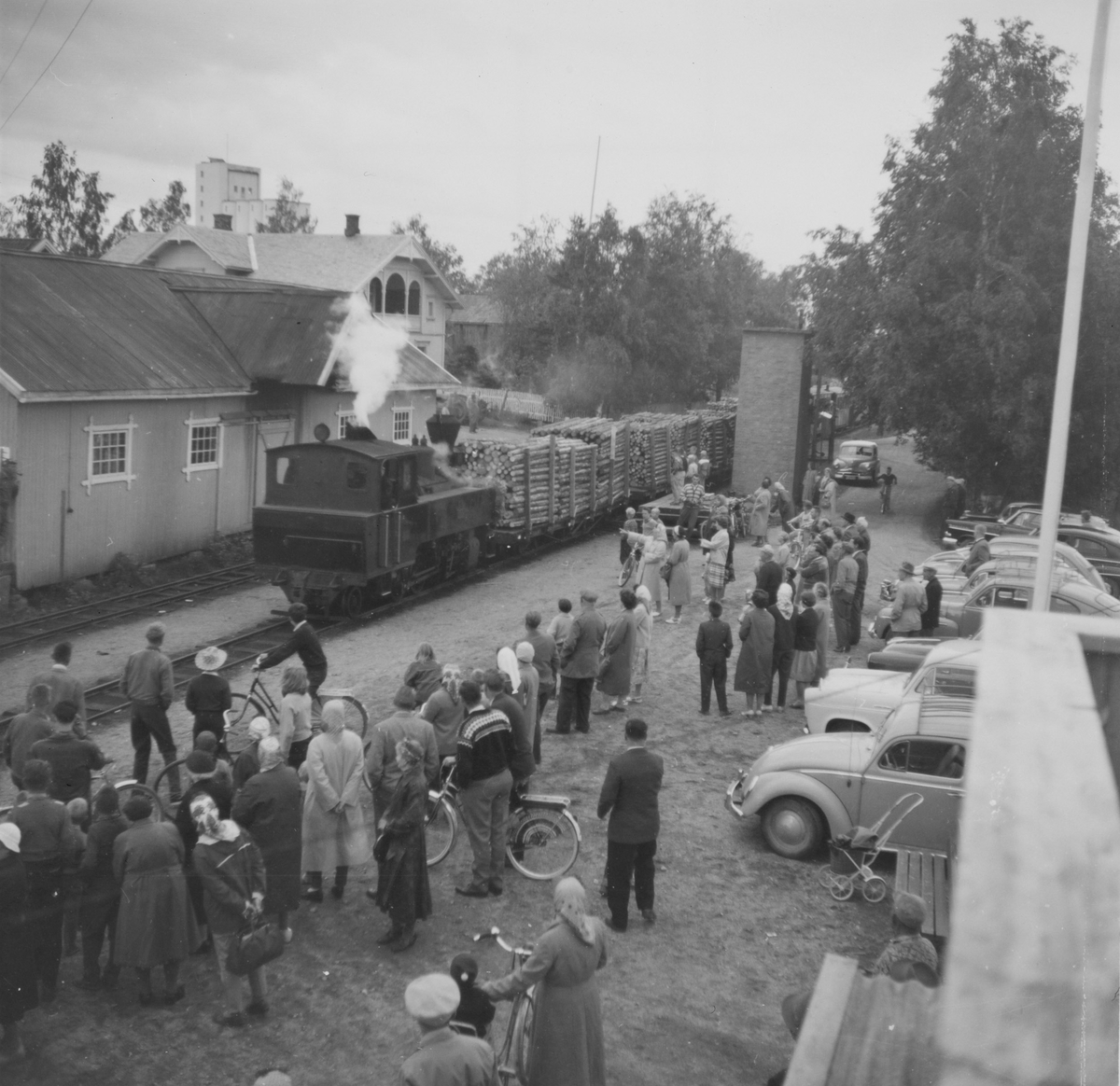 Siste ordinære tog fra Sørumsand til Skulerud kjører inn på Bjørkelangen stasjon. Lokalbefolkningen har møtt frem på stasjonen. Fotografen står i 2. etasje i stasjonsbygningen.