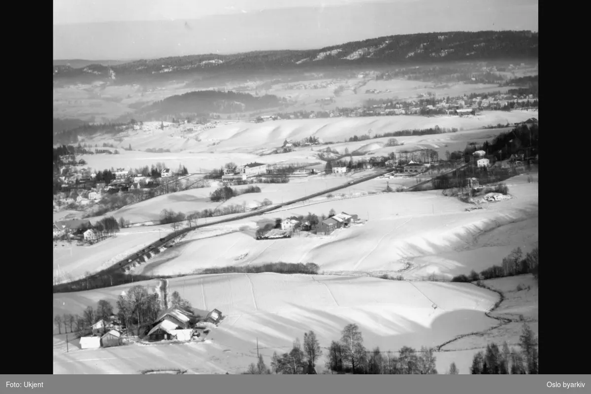 Jordbruksområde, villabebyggelse, snø (Flyfoto). Bildetittelen er noe misvisende, Furuset skole er midt i bildet, med Lindeberggårdene og Strømsveien på skrå over jordene.