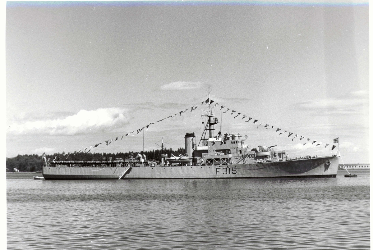 Motiv: River-kl. fregatt KNM GARM (F 315) Styrbord bredside. Stor flagging.
