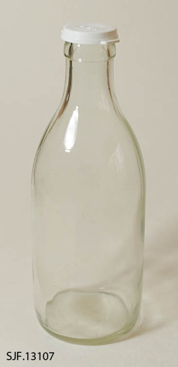 Melkeflaske bestående av flaske og lokk. Flaska er lagd av klart glass. Den er er 25,5 centimeter og har en sylindrisk kropp med 9,5 centimeters diameter. Cirka 14 centimeter ovenfor standflata skrår flaska slakt innover mot en krage rundt munningen. Her er diameteren (utvendig) 4,0 centimeter. I bunnen av flaska er det en del symboler i opphøyet relieff, blant annet noe som ser ut som en sammensmeltning av bokstavene «M» og «G» (som indikerer at dette er et produkt fra Moss Glassverk) samt «N4» og «61». Flaska kan romme et væskevolum på 1 liter. Melk ble levert i slike flasker, med en foliekapsel over flaskemunningen. For å kunne lagre rester etter at foliekapselen var brutt hadde husholdningene gjerne en del plastdeksler som kunne gjenbrukes hver gang ei flaske med melkerester skulle settes til side i påvente av at resten av innholdet skulle konsumeres.  Denne flaska ble avlevert til museet med et kvitt plastdekksel med ordet «MELK» i opphøyet relieff på oversida. Dekselet er sirkelrundt, men har to utstikkende «ører» eller «flipper», plassert diameteralt overfor hverandre, som ble brukt når dekselet skulle løsnes.