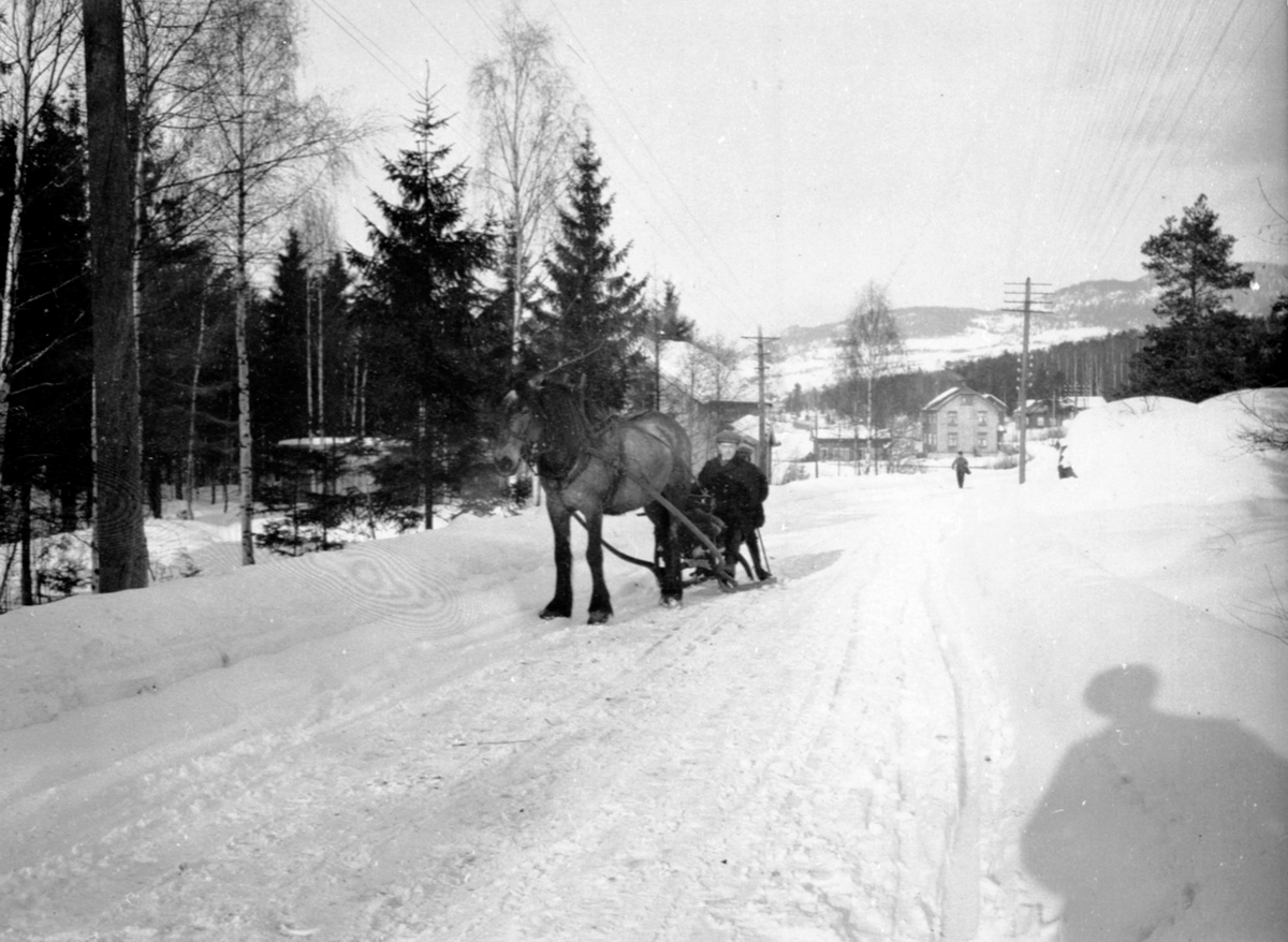 Herredsagronom Jørgen Hauger på slede med hesten "Borken" i storgata Moelv, Ringsaker. Vinter. Bildet er tatt i nordre del av Moelv, der Kafe Fønix ligger nå. Hauger brukte først hest, siden motorsykkel og til slutt bil til jobben som herredsagronom.