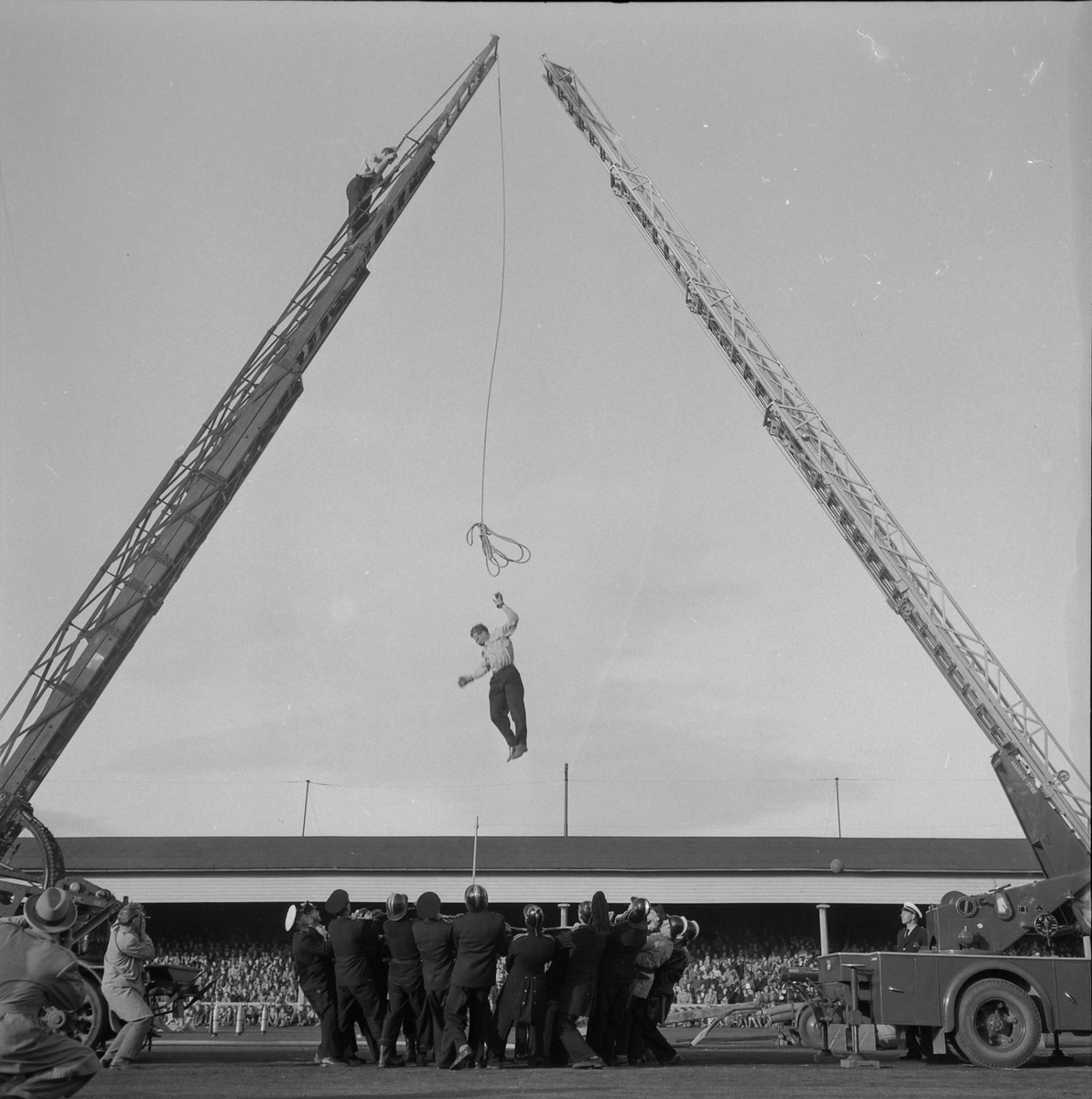 Brannmannsdagen 1955. Oppvisning på Stadion. Brannmann hopper ned i brannseil