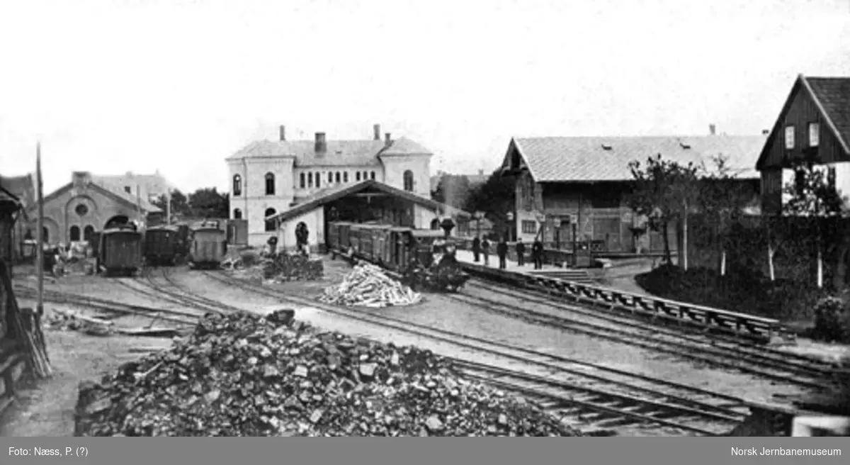 Oversiktsbilde over Trondheims første jernbanestasjon på Kalvskinnet; persontog på stasjonen