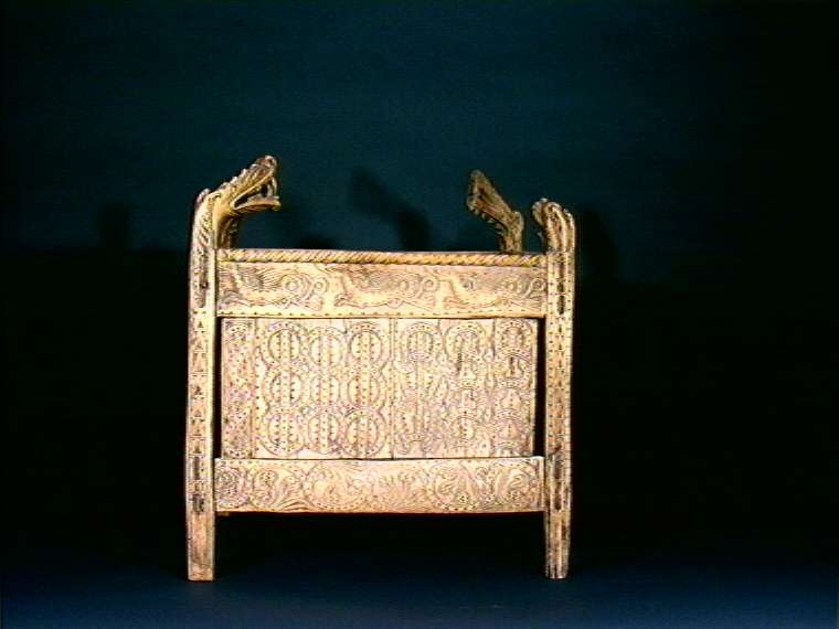 Fire søyler med skåret dyrehode-ornamentikk, sammenføyet med tverrbord og fyllinger. Bunn er åpen foruten to tverrstaver. Hele utsiden er rikt dekorert med utskåret dyr og ranker.