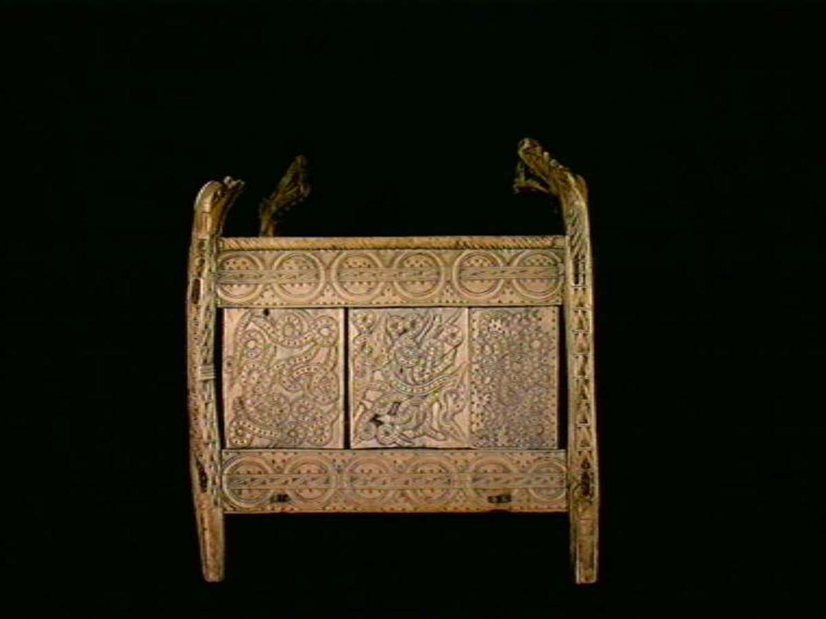 Fire søyler med skåret dyrehode-ornamentikk, sammenføyet med tverrbord og fyllinger. Bunn er åpen foruten to tverrstaver. Hele utsiden er rikt dekorert med utskåret dyr og ranker.