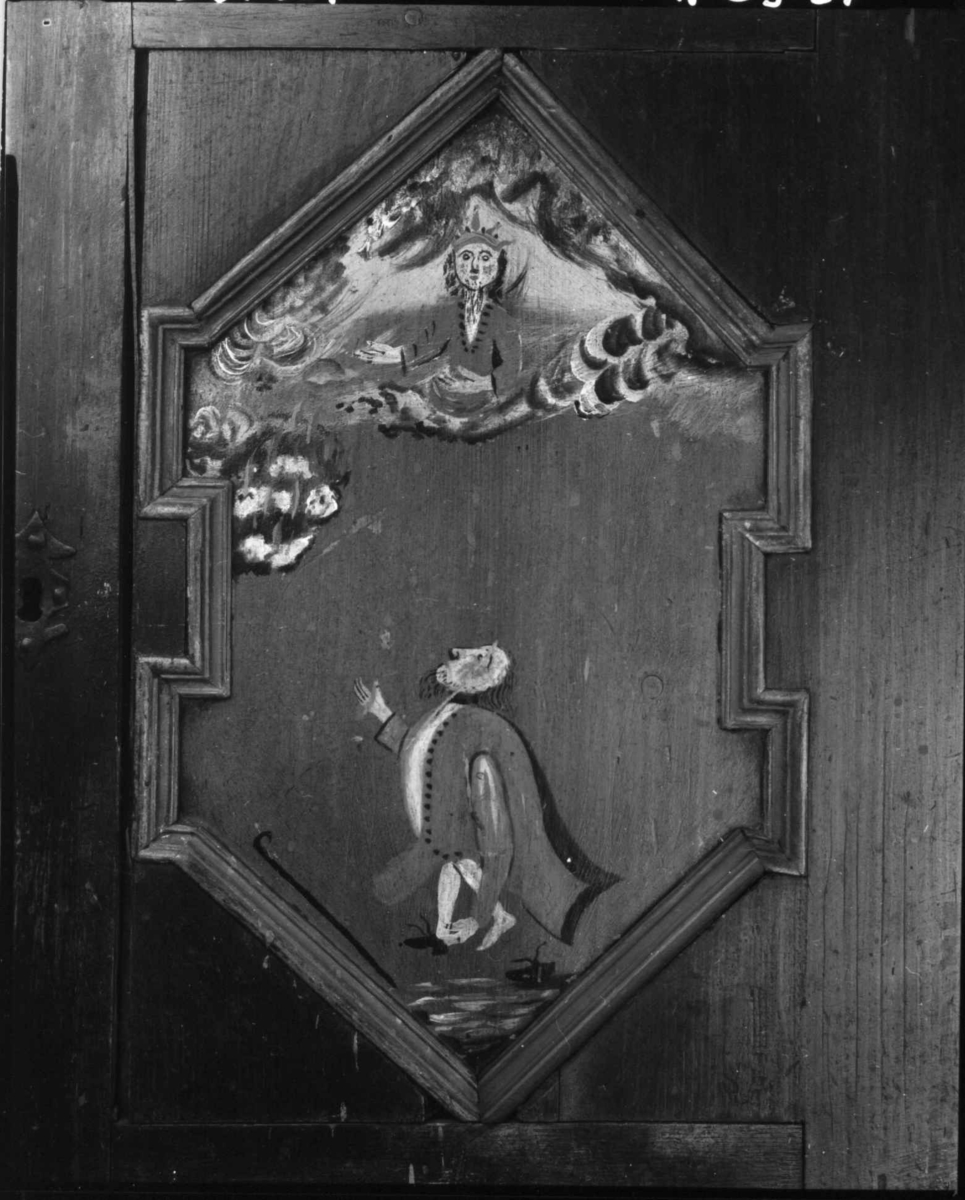 Skap, framskap i en del, to dører oppe og nede. Bibelske motiver; Moses og de ti bud. Gud på en sky, en brennede sky eller busk, en mann som har mistet en sko og en stokk.