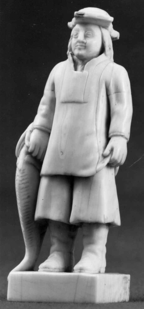 Mannsfigur med fisk i hånden.
