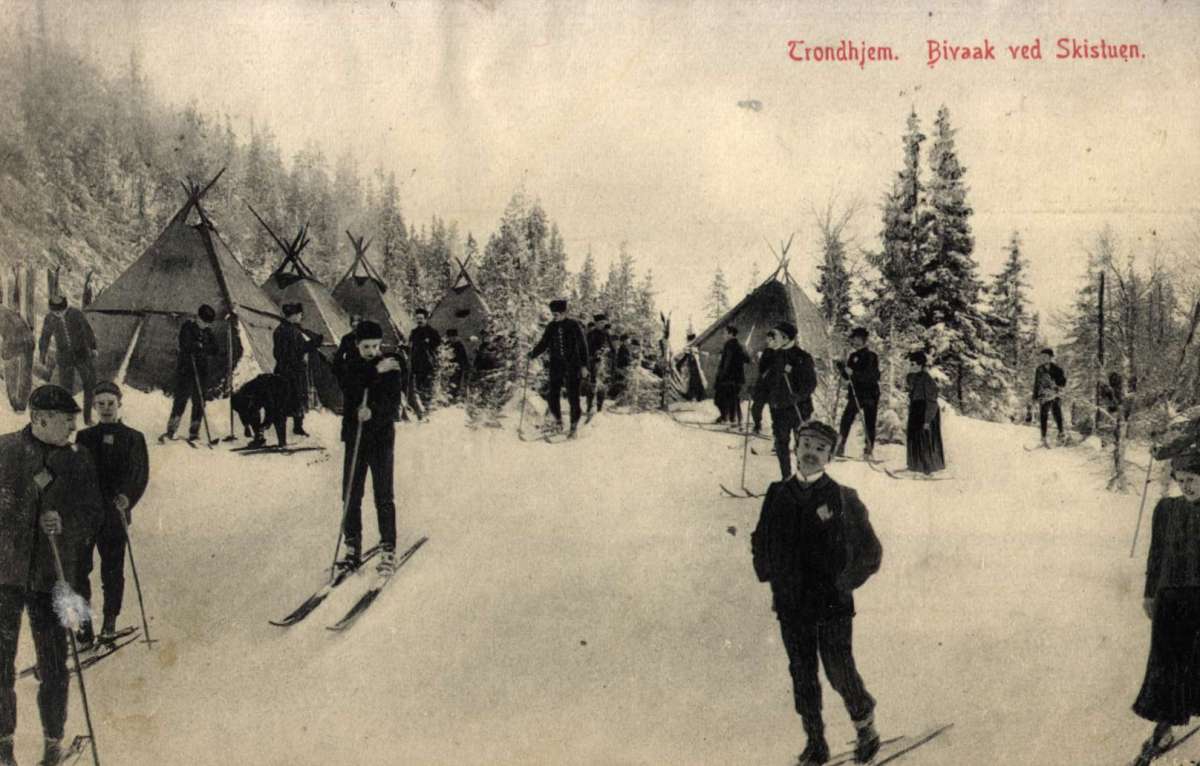 Postkort. Jule- og nyttårshilsen. Foto. Svart/hvitt. Vintermotiv. Bivuakk ved Skistua i Trondheim. Skiløpere.
Stemplet 24.12.1907.