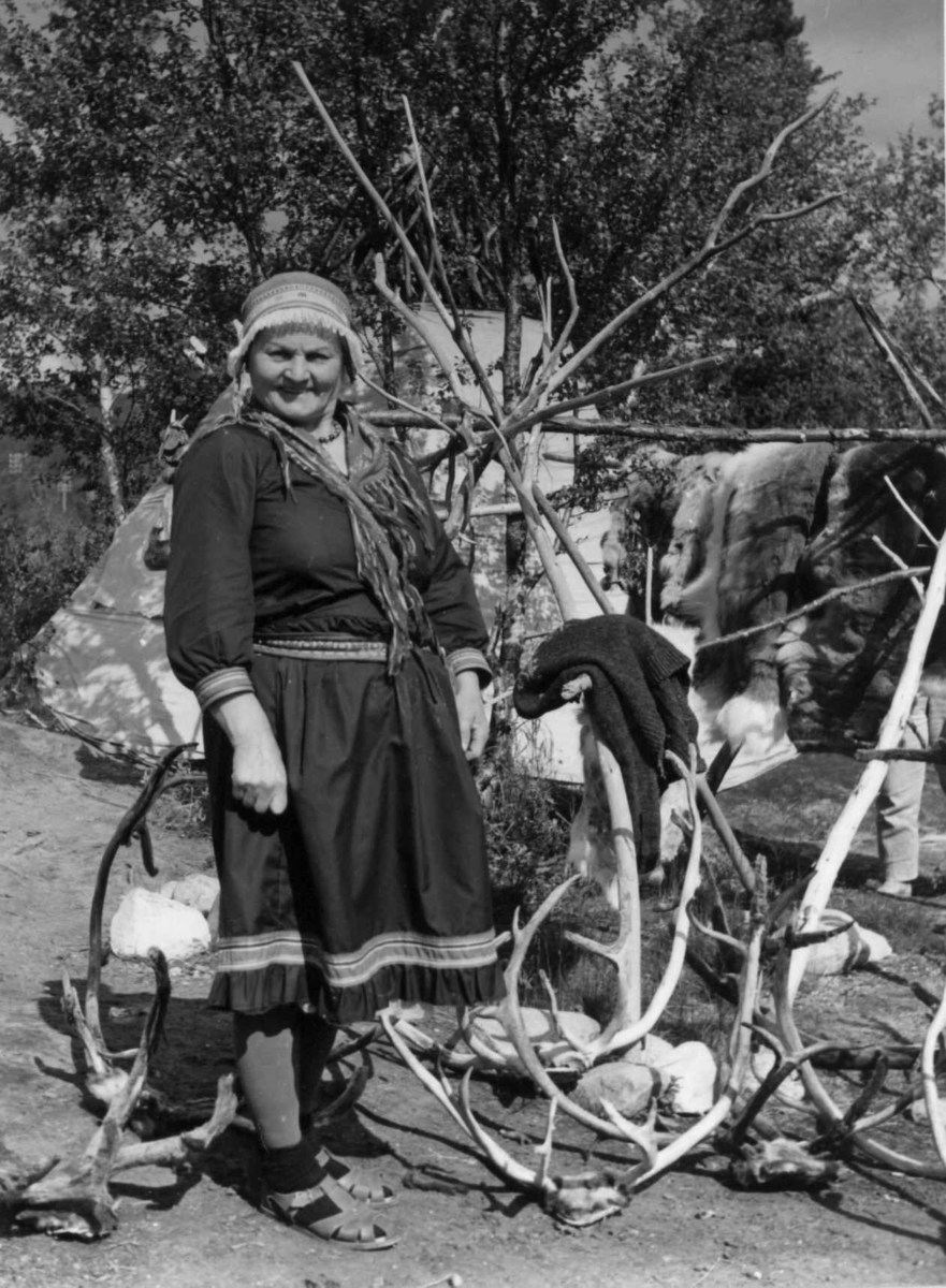 Ella Blind foran sitt souvenirutsalg med reinsdyrhorn og reinsdyrskinn. Lønsdal 1964.