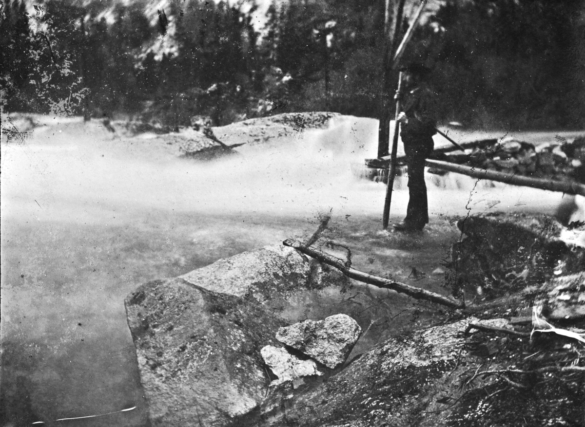 Mann ved elv,muligens damanlegg, antatt ved Hegglandsgrend, Fyresdal, Telemark. Bildet er tatt under en stor flom i området 1880.