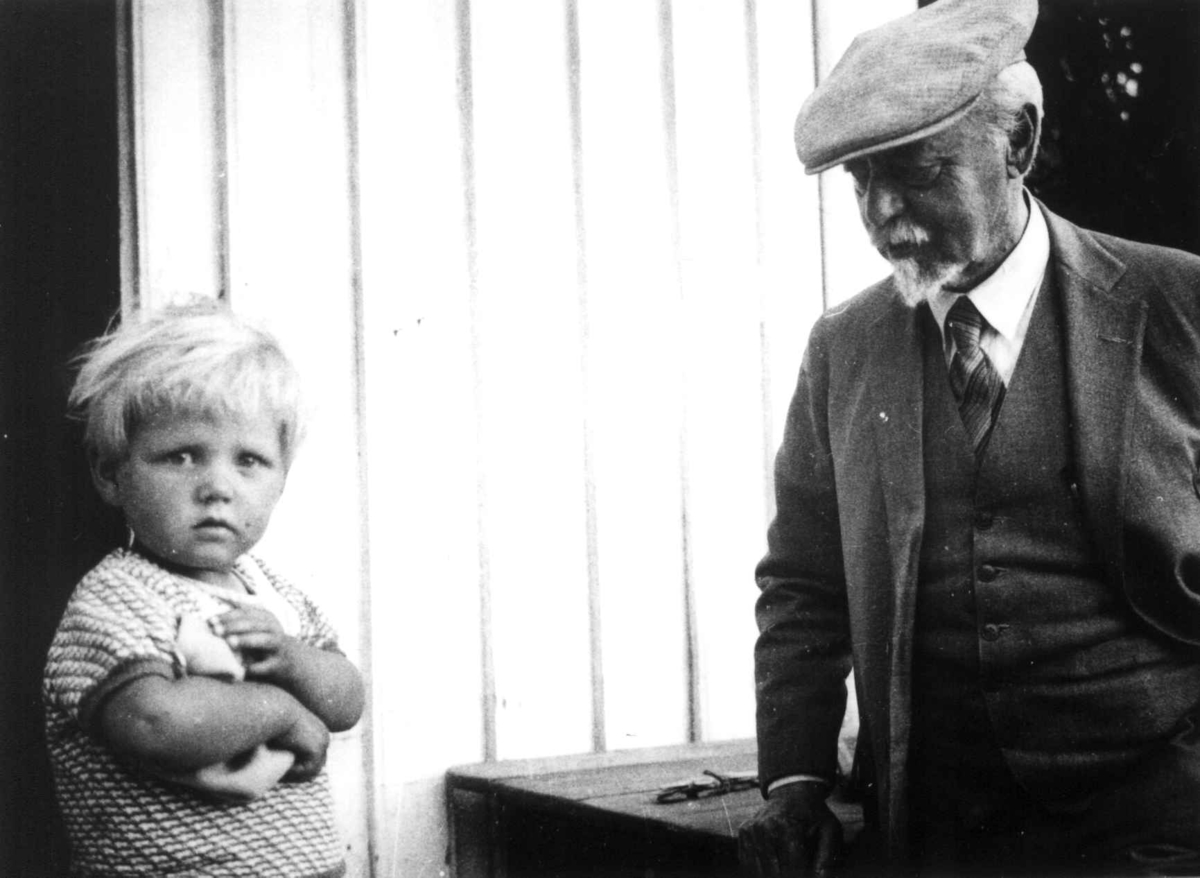 Kunstmaler Müller står henvendt til en liten gutt utenfor et hus. Tveit,  Kristiansand 1937.