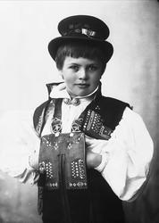 Studioportrett av ung gutt i drakt og hatt.