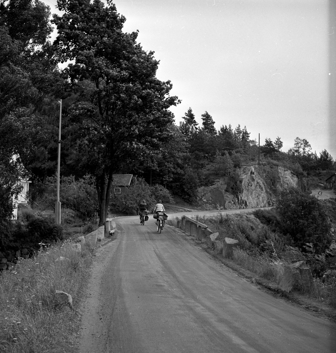 Riksvei 40 ved Risør. To syklister og hus med uthus.