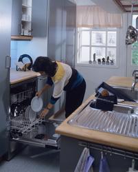 En kvinne rydder ut av oppvaskmaskin. lllustrasjonbilde fra 