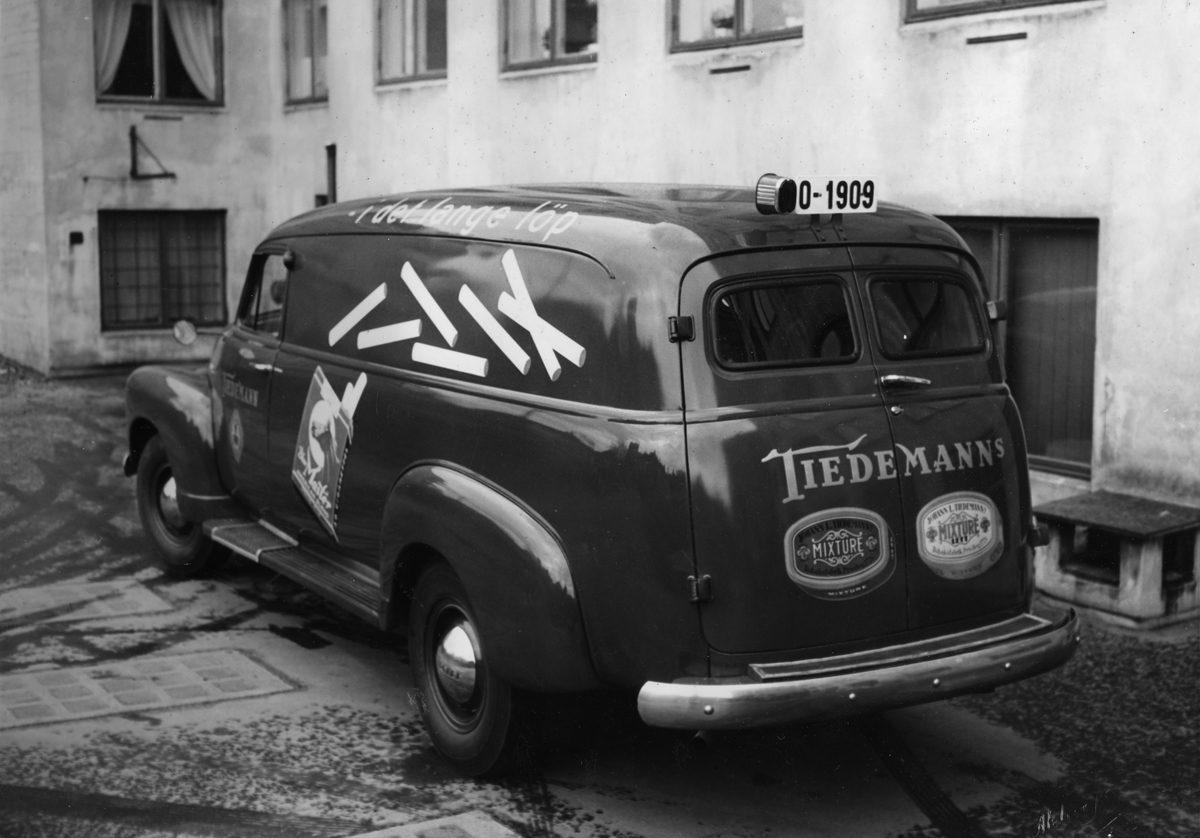 Gatebilde. Bil med reklame for Tiedemann og Blue Master sigaretter.