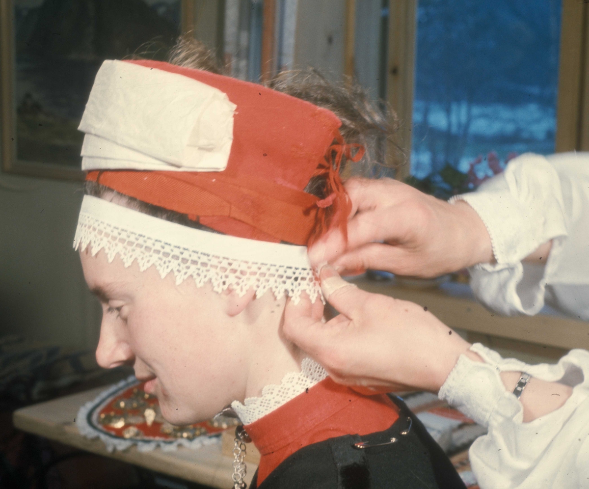 Brudepynting, Jølster 1967.Bruden, Eva Eide, får hjelp av Maria Gjesdal  med påkledningen.
Pannelinet settes på.