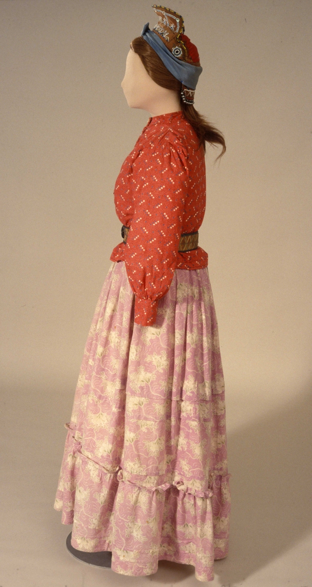 Skoltesamisk drakt på dukke i den samiske utstillingen på Norsk Folkemuseum. Figuren er sett fra siden. sett fra siden.
Bluse SA.2435A
