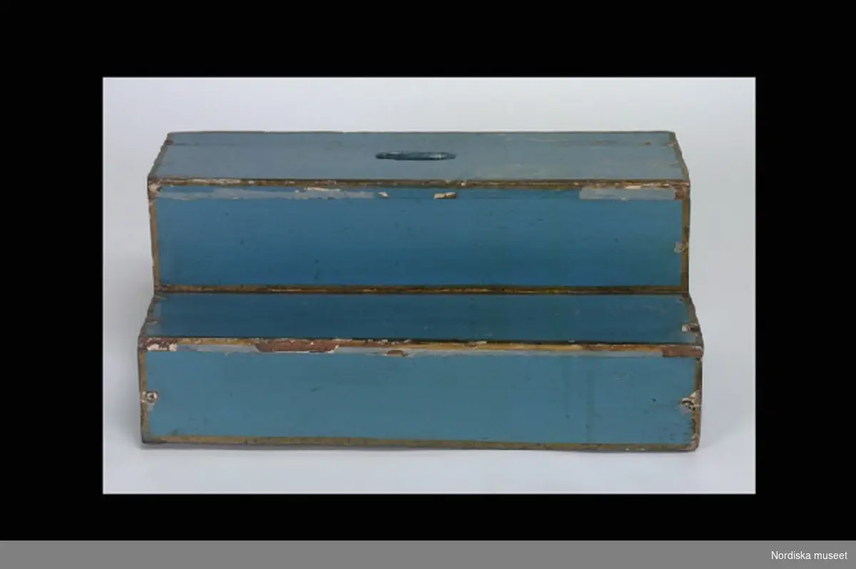 Inventering Sesam 1996-1999:
L 110  B 45  H 215 (cm)
Dockskåp i fyra våningar (a), rokoko, av furu, målat i blått med förgyllda lister, uppdraget krön och avfasade hörn. Glasad och spröjsad dörr. Förgyllda rokokobeslag och springlås, pinnhängen.
b+) Löst underrede med låda på 6 st svängda ben. 
c) Spis, öppen härd, kvadratisk form, av gråmålat trä.
d) Fotpall (sekundär), rektangulär, av blåmålad furu med guldkanter, två steg, övre trappsteget med ovalt urtag.
e) Nyckel.
1:a våningen:
Kök med målat brunt stengolv. Porslinskök med målat grönt stengolv. Gråmålade väggar.
2:a våningen:
Sovrum och gemak, grönmålade väggar med rokokoornamentik i guld. Sal, rosamålade väggar med  rokokoornamentik i guld. Målade parkettgolv i olika utförande.
3:e våningen:
Väggar med målad bröstpanel och landskapsmålningar. Svart- och vitrutigt målat golv.
4:e våningen:
Målad bröstpanel. Rödmålad vägg med gul rokokoornamentik. Målade parkettgolv.
Har tillhört Maria Catharina Falck (1752-1801), g. med Carl Fredrik Ekerman, justitieborgmästare i Stockholm.
Möbler, husgeråd m.m. från 1700-talets mitt - 1800-talets mitt, se inv nr 151.826-152.006. Fajansservis (inv.nr 114.397-114.400) Rörstrand, sign. 1746. Porträtt föreställande bl a fam. Falck och Ekerman. Skåpet har tidigare varit målat i vitt med förgyllda lister, jfr foto från 1909 på äldre katalogkort.   
  
Anna Womack 1996