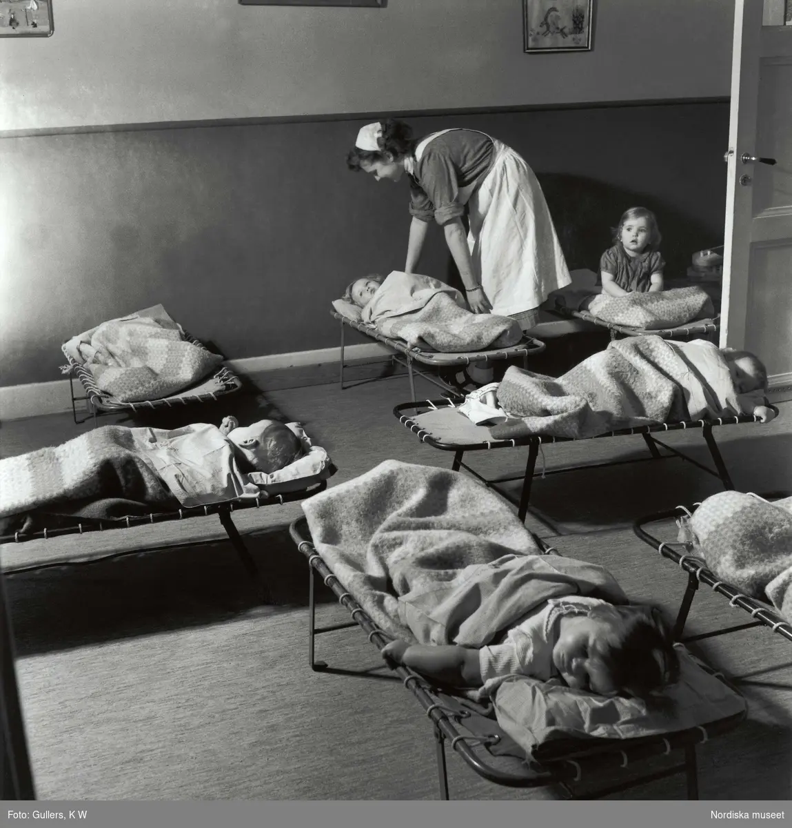 Sovande barn på daghem, barnkrubba, stoppas om av barnsköterska.