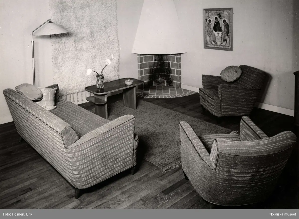 Vardagsrum ed två fåtöljer, en soffa samt en öppen spis i ena hörnet. Nordiska Kompaniet. Arkitekt A. E. Hjort, utställningen ”Vackra möbler” i maj 1937.
