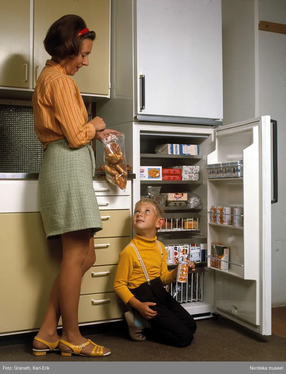 Kök. Kvinna och barn vid öppet kylskåp.