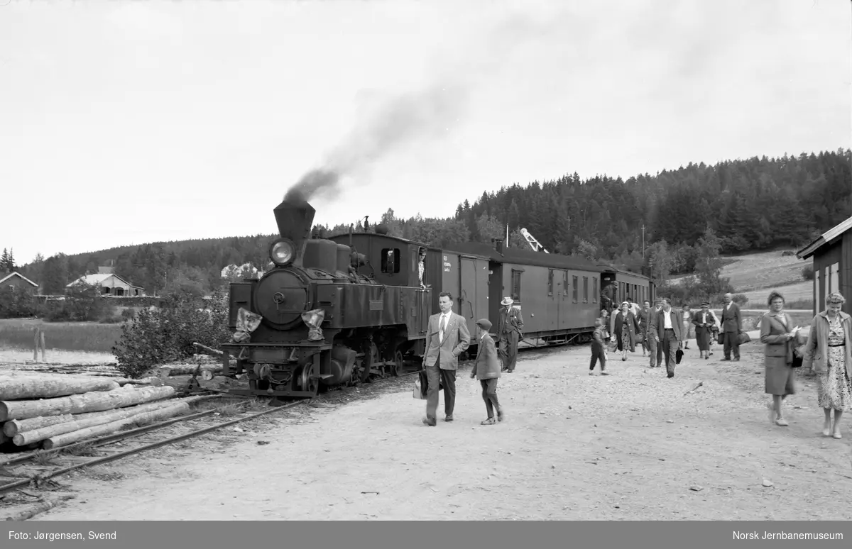 Persontoget, trukket av damplokomotiv nr. 4 "Setskogen", har ankommet Skulerud stasjon, hvor de reisende skal videre med D/S Turisten