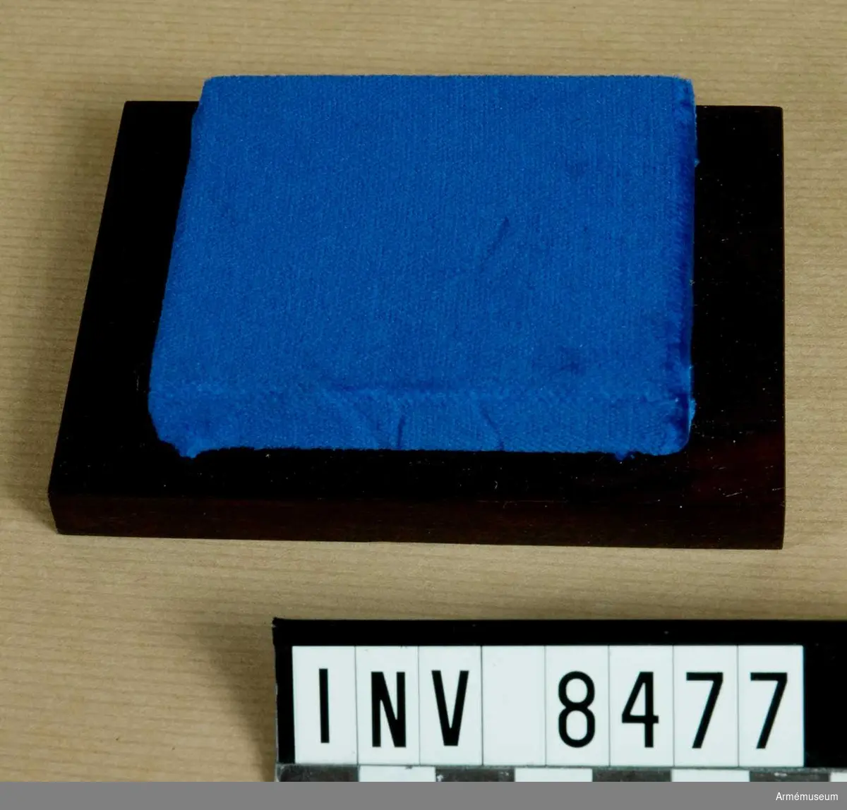 Samhörande nr AM 8475-8478.
Förvaringslåda till AM 8475 och 8476.
Lådans golv är en brunbetsad platta. På denna platta är en sammetsöverklädd platta. På den sammetsöverklädda står den lilla miniatyrkannan.
