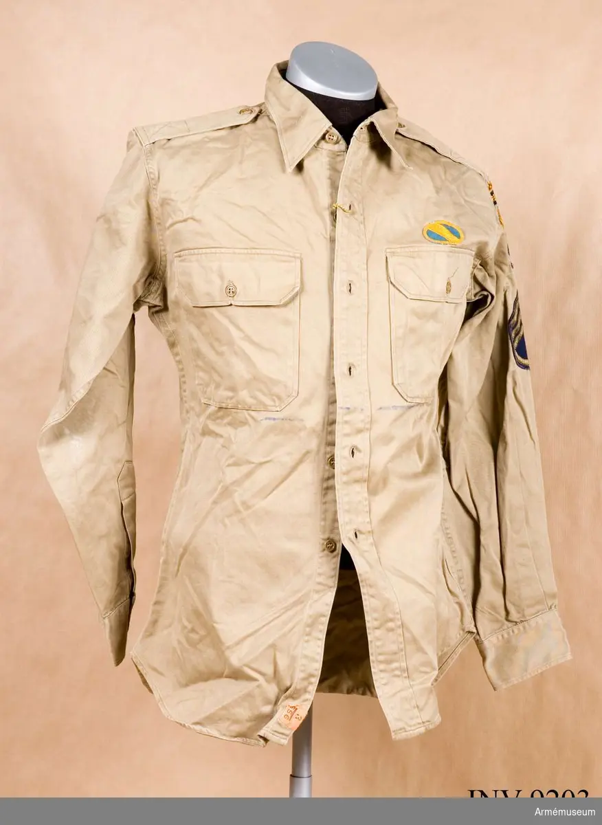 Skjorta, Special Forces U S Army 1960, sergeant. Sydd i grågrön (beige) bomullskhaki, ett impregnerat tyg. Två bröstfickor med lock och knäppning, krage på stånd och enkla manschetter. Skjortan har ok i ryggen och fasta axelklaffar. På vänster sida strax ovanför fickan ett ovalt gult och blått märke.
På vänster överärm överst ett märke där det står RANGER. Under det ett märke där det står AIRBORNE. Under det ett granatformat märke, blå botten och ett gult svärd med tre blixtar (Special forces insignier). Under det gradbeteckningen för sergeant. På höger överärm samma grabeteckningsmärke. Skjortan är nedtill på avigsidan märkt "K 6895. Edmund Kolby, 626 Coral Way, Florida 33134".
Källa: Army Badges and insignia since 1945 Book one. Blandford Colour Series.