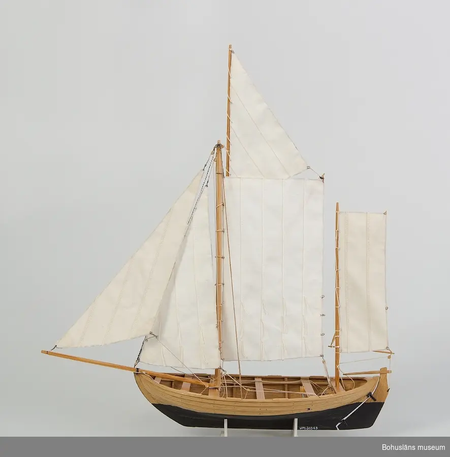 Modell av kåg, rundgattad klinkbyggd öppen segelbåt, vanligen ca 20 fot lång. Riggad med sprisegel, toppsegel, fock, klyvare samt mesansegel (råsegel).