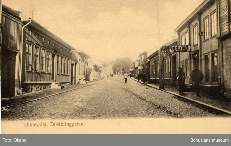 Tryckt text på vykortets framsida: "Uddevalla, Drottninggatan."
"Uddevalla Pappershandel, Hildur Anderson."
Till höger i bild hänger en skylt med texten C. G. Rydin