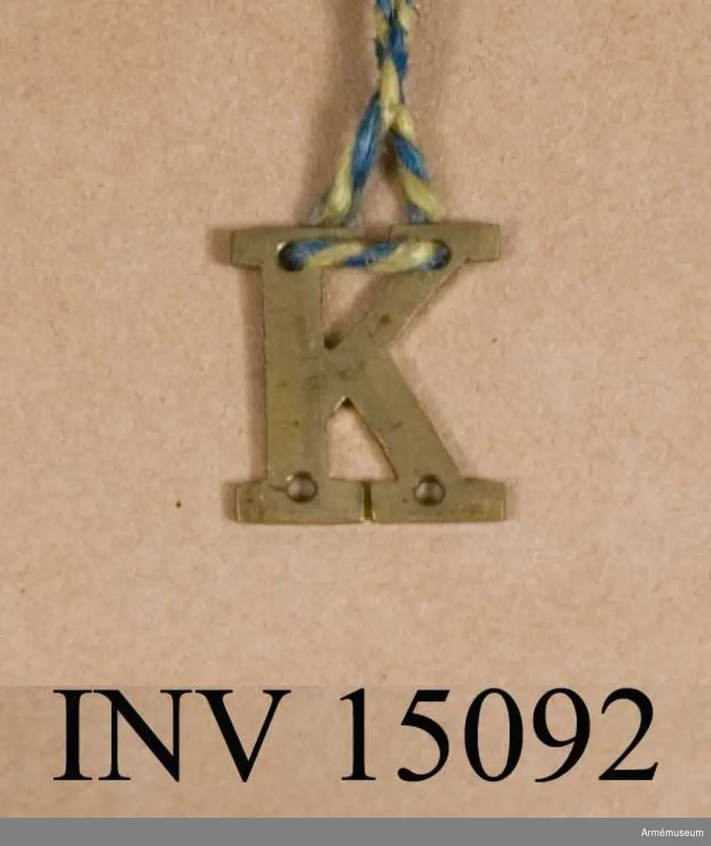 Grupp C I
Bokstaven K m/1915 till lägermössa och hatt. För manskap vid infanteriets kulsprutekompanier.
Fastställd genom go nr 1591 den 12 november 1915.