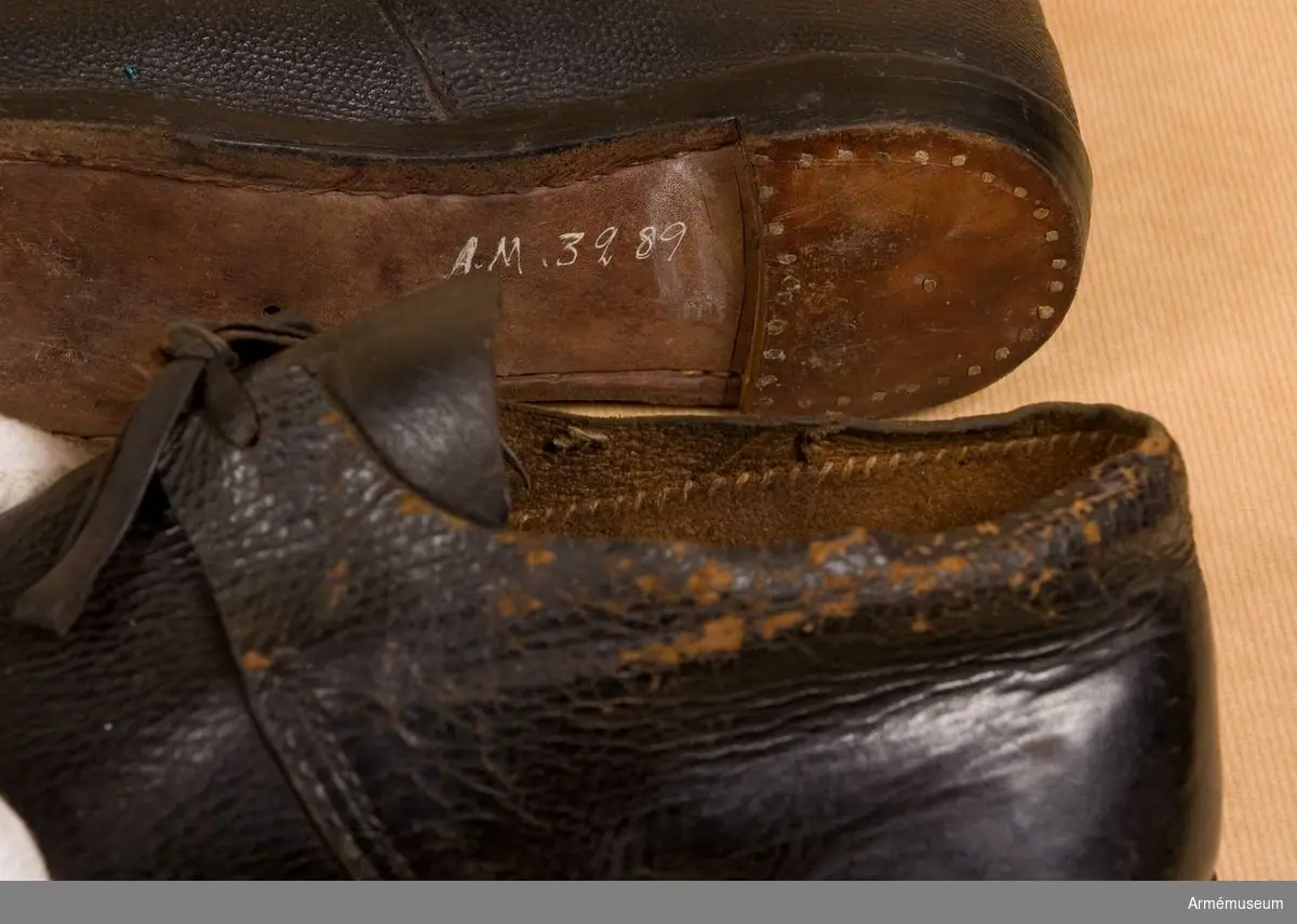 Skor av brunt läder.
Den ena skon har spår av rött lacksigill och är därför ett modellexemplar. Den andra skon är med största sannolikhet en replika.