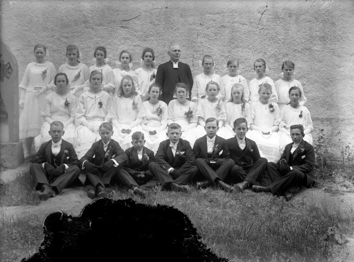 Konfirmandgrupp, sannolikt vid Vallby kyrka (östra gaveln), Uppland. I mitten sannolikt kyrkoherde Gustaf Thegerström (1853-1937).