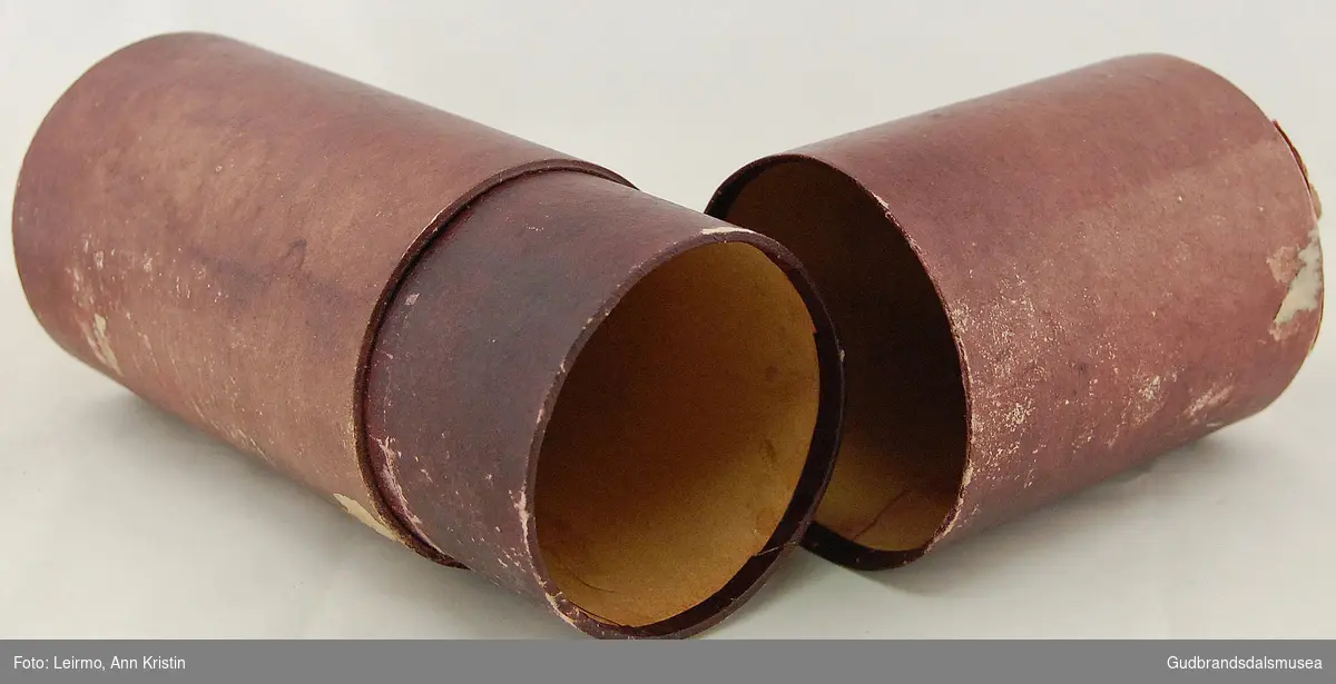 Sylinderformet burgunderfarget futteral i papp.