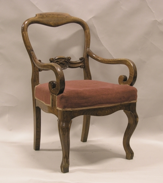 Stol med rygg- och armstöd, stoppad sits klädd med rött tyg.
Stolen är mjukt formad och den genombrutna ryggen har en ornamenterad
tvärslå.
