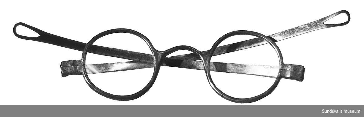 Ett par glasögon med båge i silver stämplade AGÅ, S, D7. De är tillverkade av Adam Gabriel Åberg (1857-1919), i Sundsvall 1906.