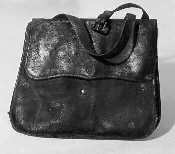 Postväska för gående postbud i svärtat läder. Väskan försedd med ställbar bärrem. Över öppningen viks en klaff som fästas på framsidan runt en metallknopp.