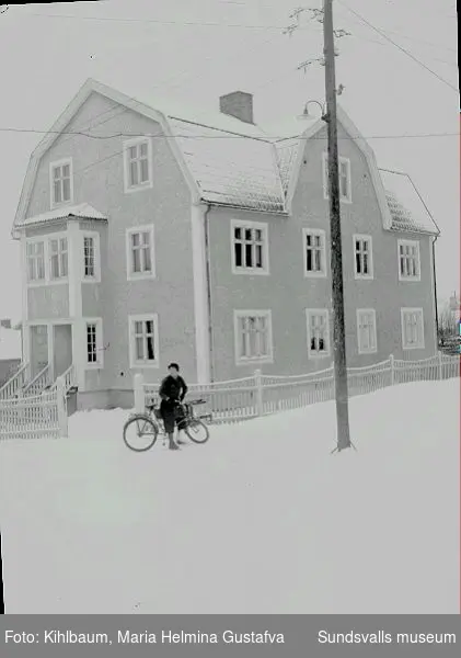 Kvinna på cykel utanför ett bostadshus på Thulegatan 43.