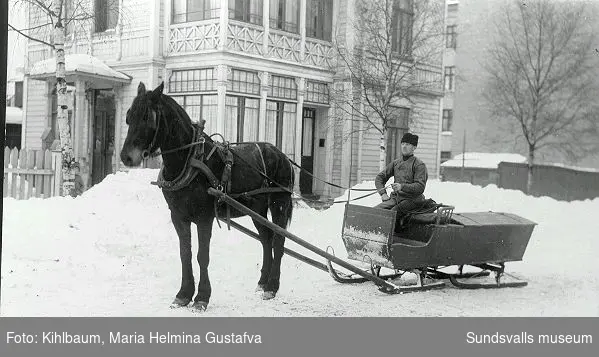 Man med häst och släde vid Nybrogatan 30. Huset bakom revs 1955.