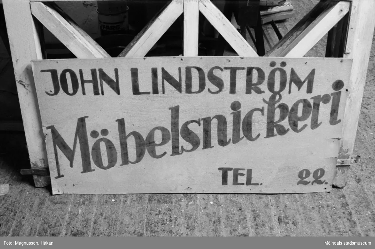 En skylt med texten: "John Lindström Möbelsnickeri, Tel 22", Backen 2:10 i Kållered år 1990. Skylten finns nu (år 2020) i Kållereds Hembygdsförenings samlingar.