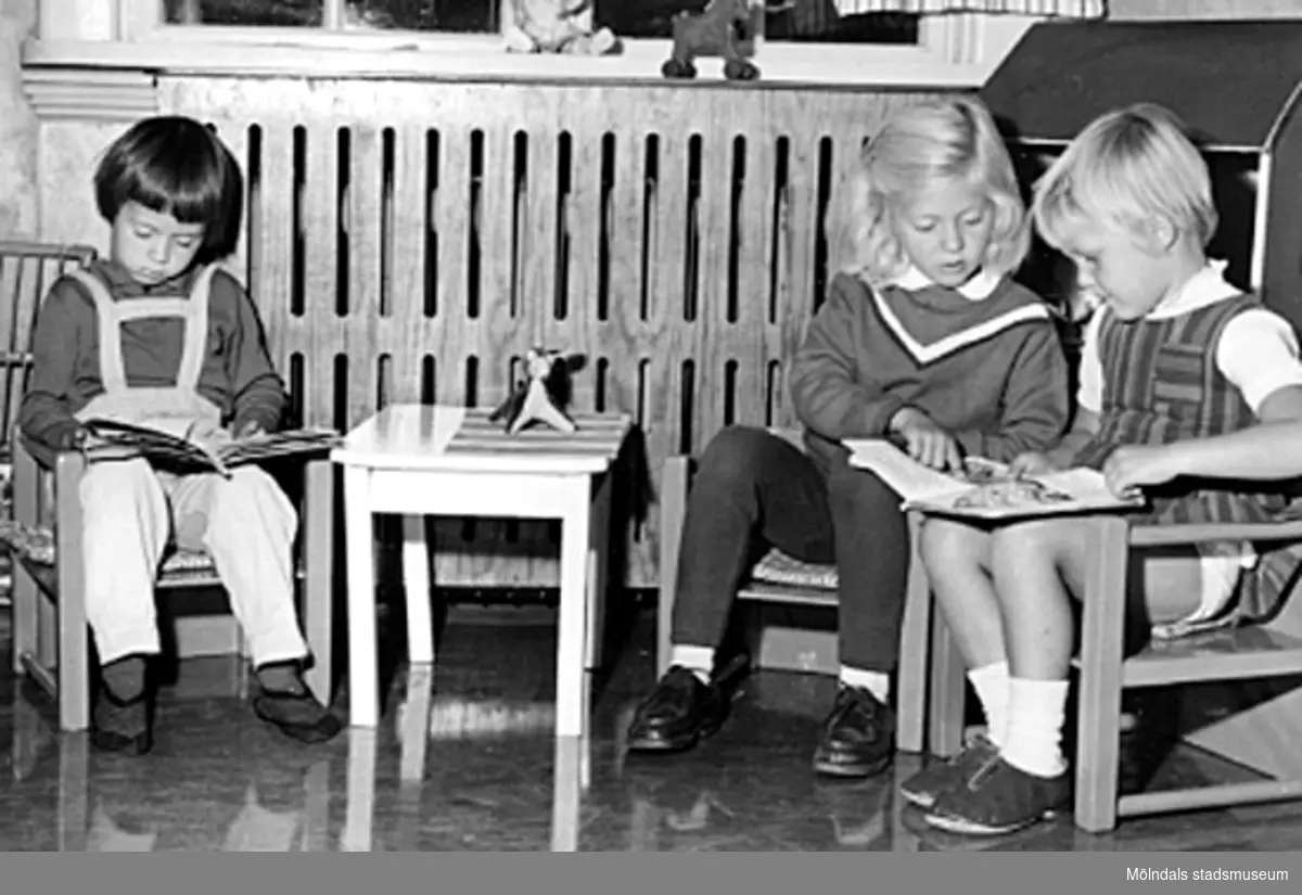 Tre flickor sitter vid ett litet bord och läser. Holtermanska daghemmet 1953.