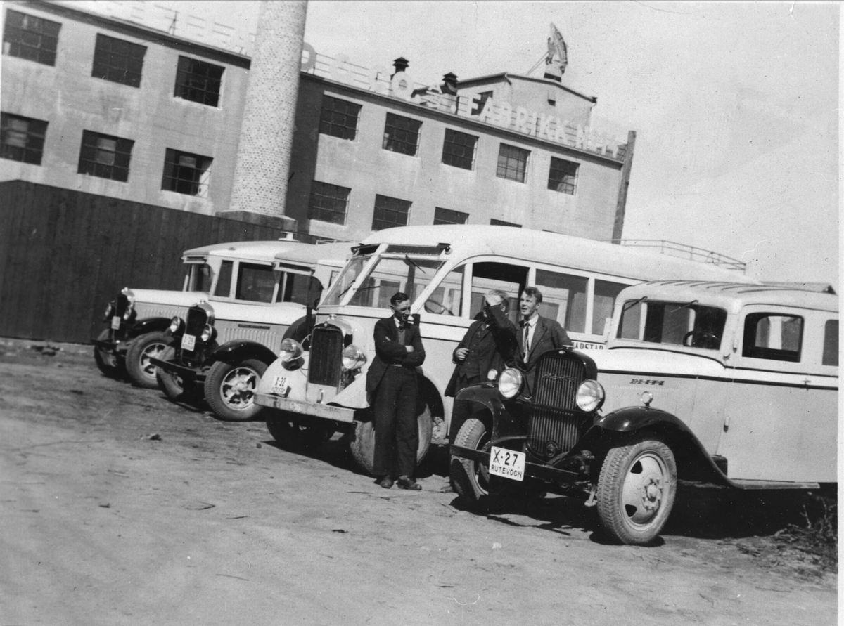 Tre sjåfører med busser ved HORB-verkstedet på Hamnneset. Bjellands fabrikk i bakgrunnen.